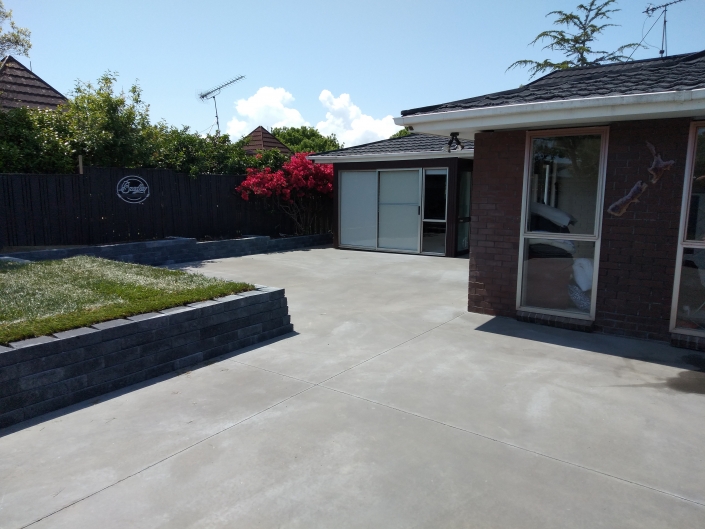 Landscaped patio - coloured concrete, retaining wall and turf laid.